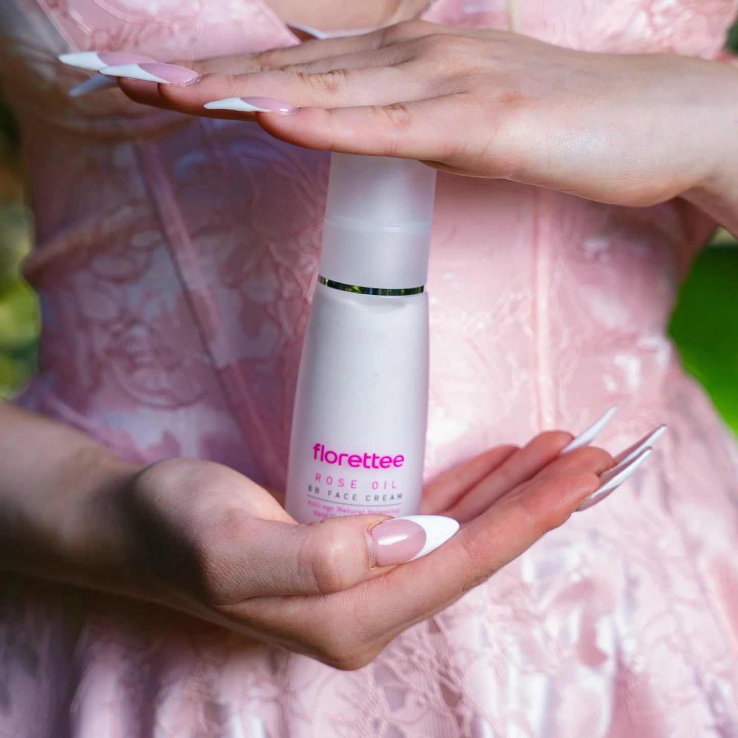 Florettee Rose Oil BB Face Cream held between hands against a pink background