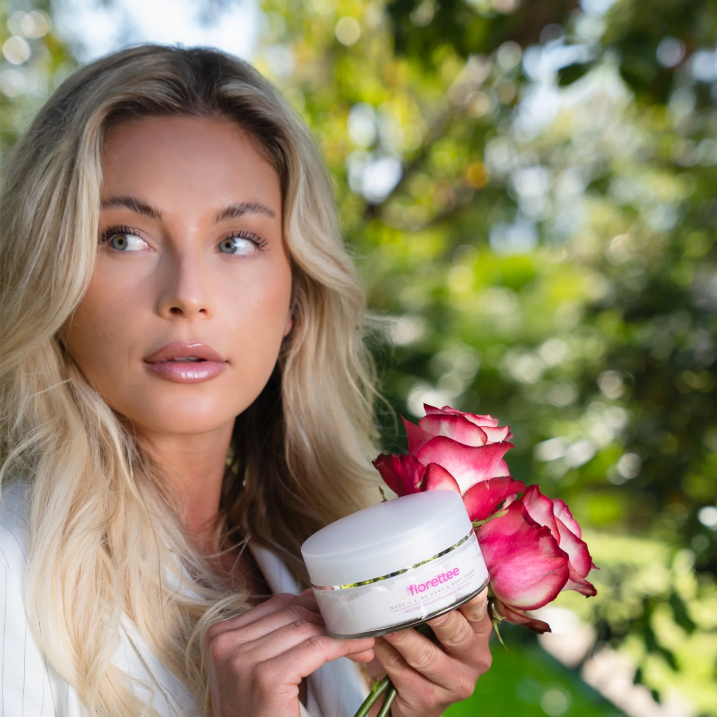 odel holding Florettee Rose Oil Hand and Body Cream with pink roses