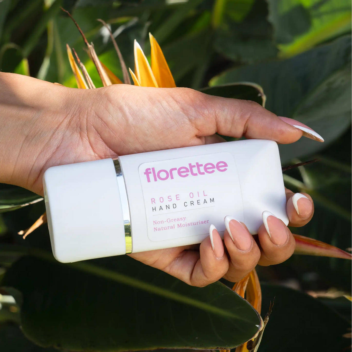 Florettee Rose Oil Hand Cream held against tropical leaves